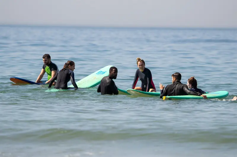 Surf group sitting on their boards in the water, chatting between waves