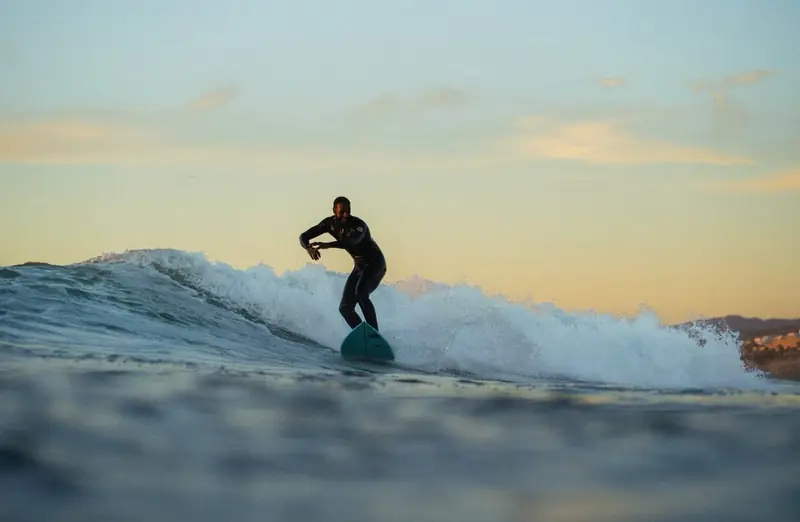 Surfer riding a wave in golden sunset light off Tamraght