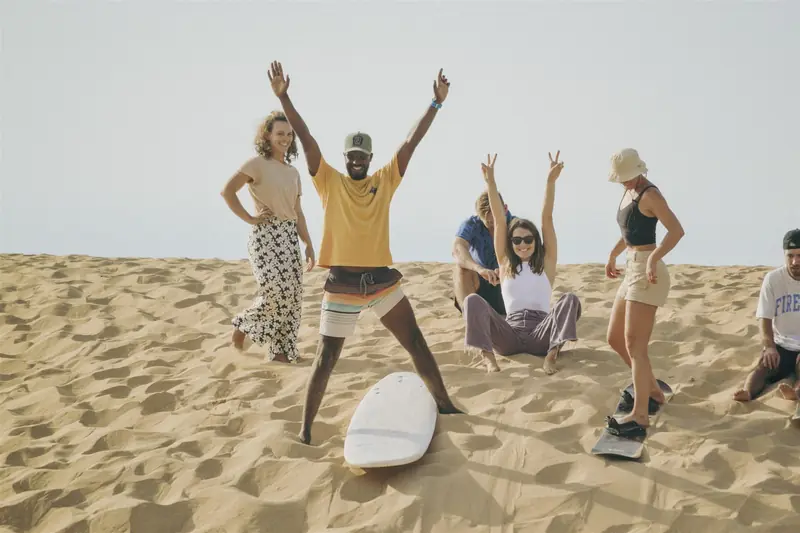Group of friends cheering on the sand near Tamraght on a NAVA trip